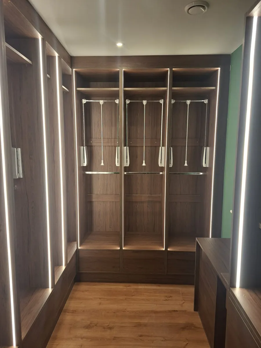 Walk-in wardrobe storage with integrated lighting and hanging rails.
