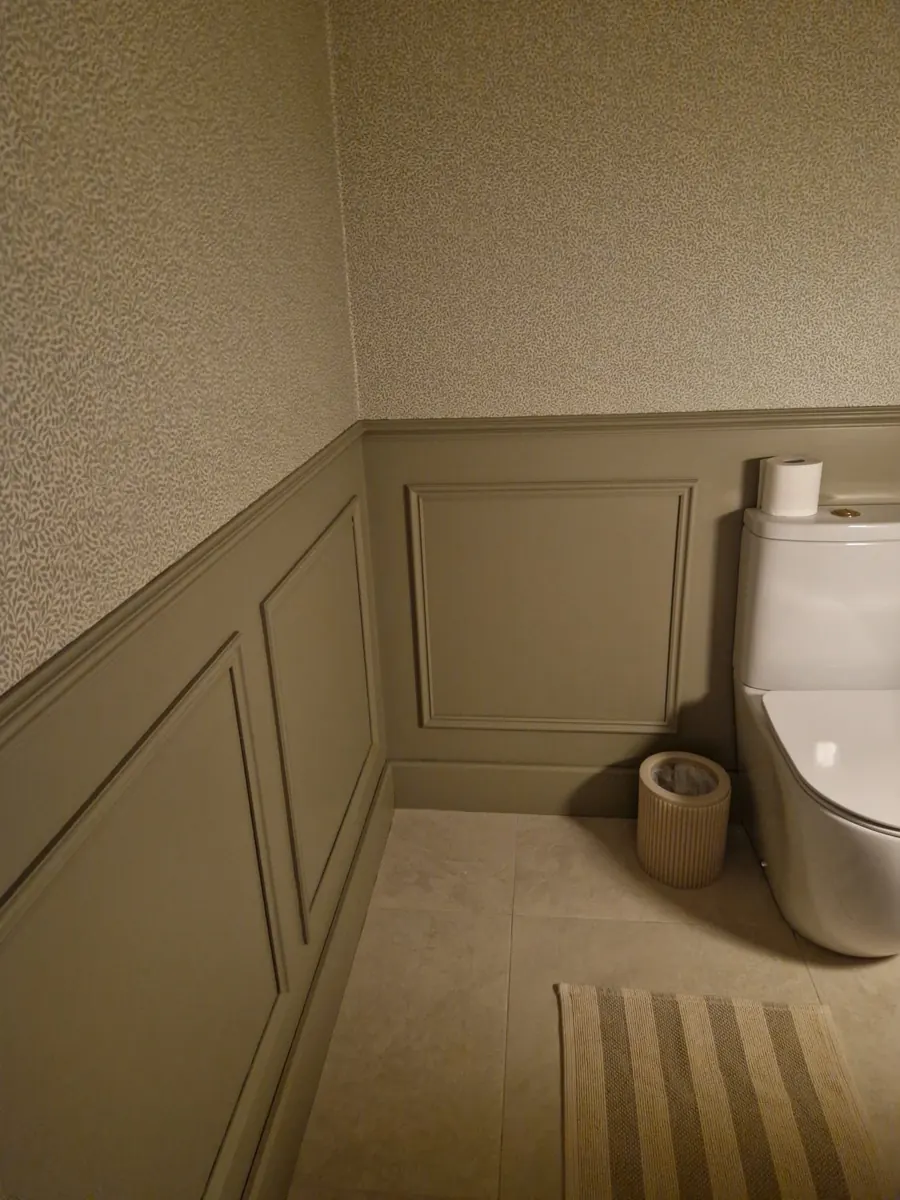 Decorative bathroom wall panelling fitted below patterned wallpaper.