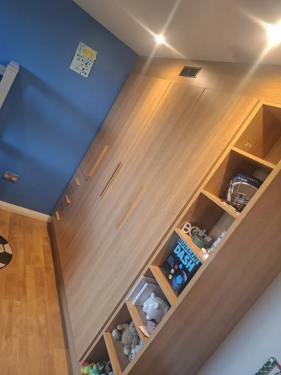 Fitted bedroom wardrobe and open shelving in a child's bedroom.