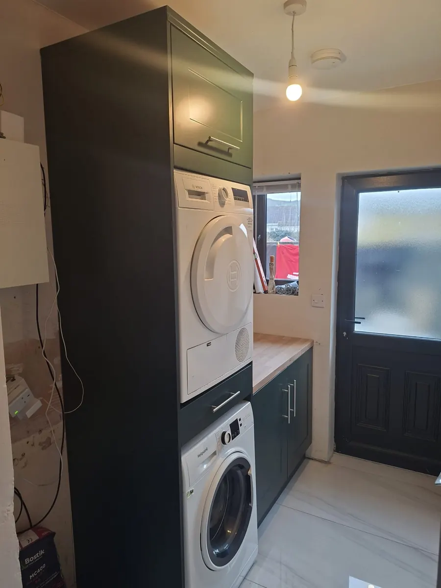Utility laundry storage and appliance housing fitted beside a door.